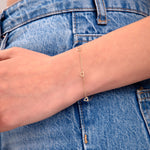 Delicate gold bracelet with open heart shapes, styled on wrist, paired with high-waisted blue jeans

