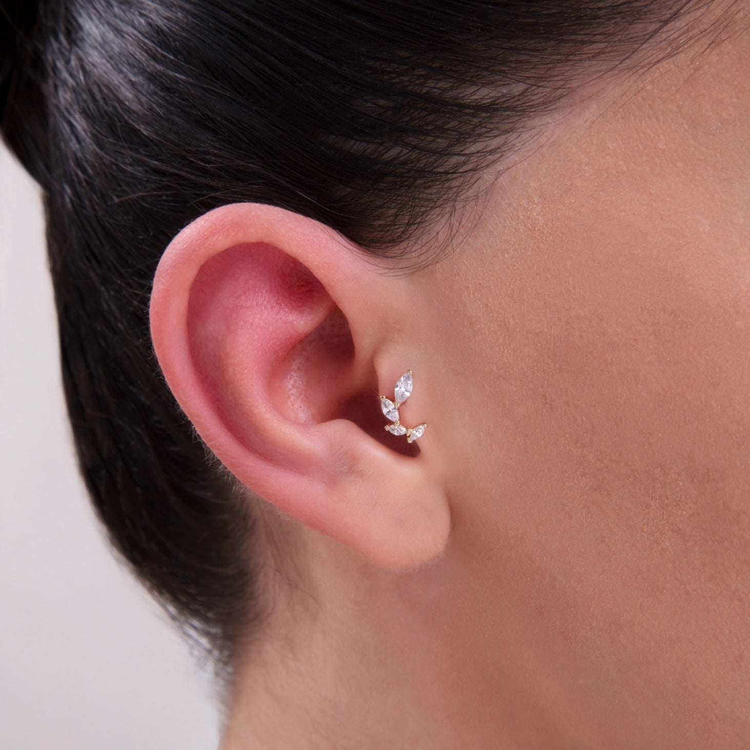 Model wearing a 14K Gold Leaf-Inspired CZ Cartilage Stud – A delicate three-marquise stone earring mimicking a leafy branch, ideal for conch, tragus, or helix piercings in a nature-inspired ear stack.