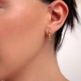 Model wearing mini gold faceted hoop earring

