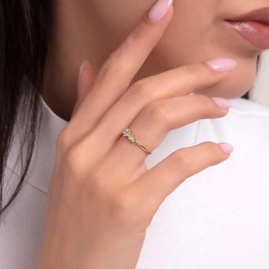 Gold ring with clustered zircon stones, worn on index finger, minimalist and elegant