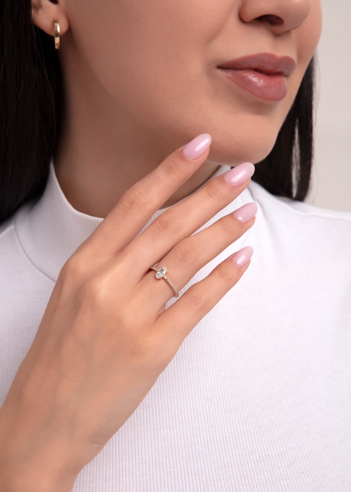 Elegant oval cut ring on woman's hand with pavé gold band, engagement-style jewelry