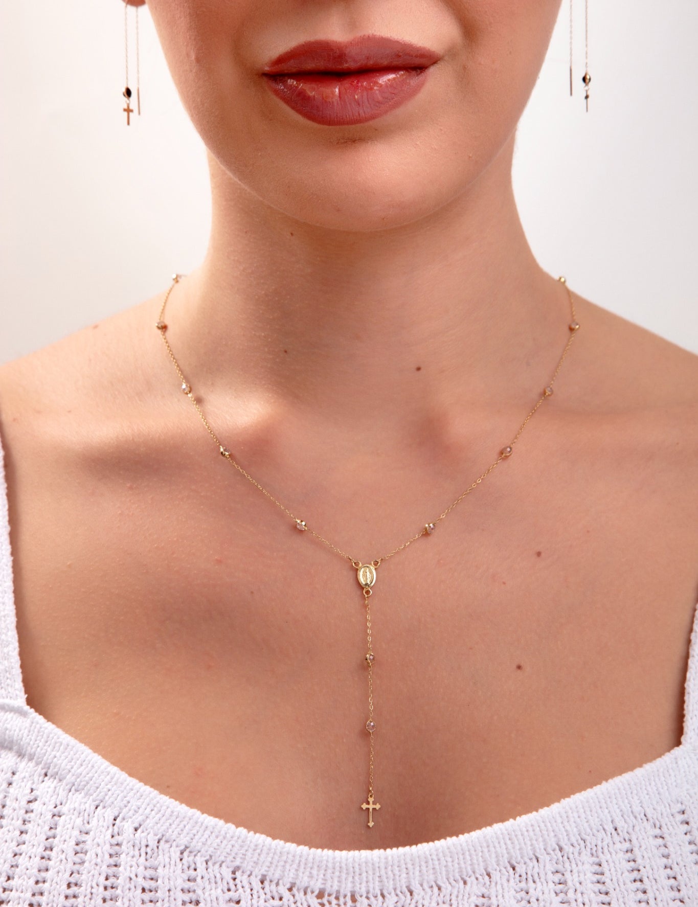 Model wearing a 14K gold plated rosary-style necklace with cross drop and Virgin Mary charm, plus matching threader earrings