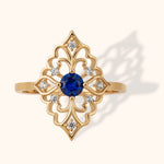 Gold filigree ring with round blue sapphire center and surrounding diamonds
