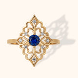 Gold filigree ring with round blue sapphire center and surrounding diamonds