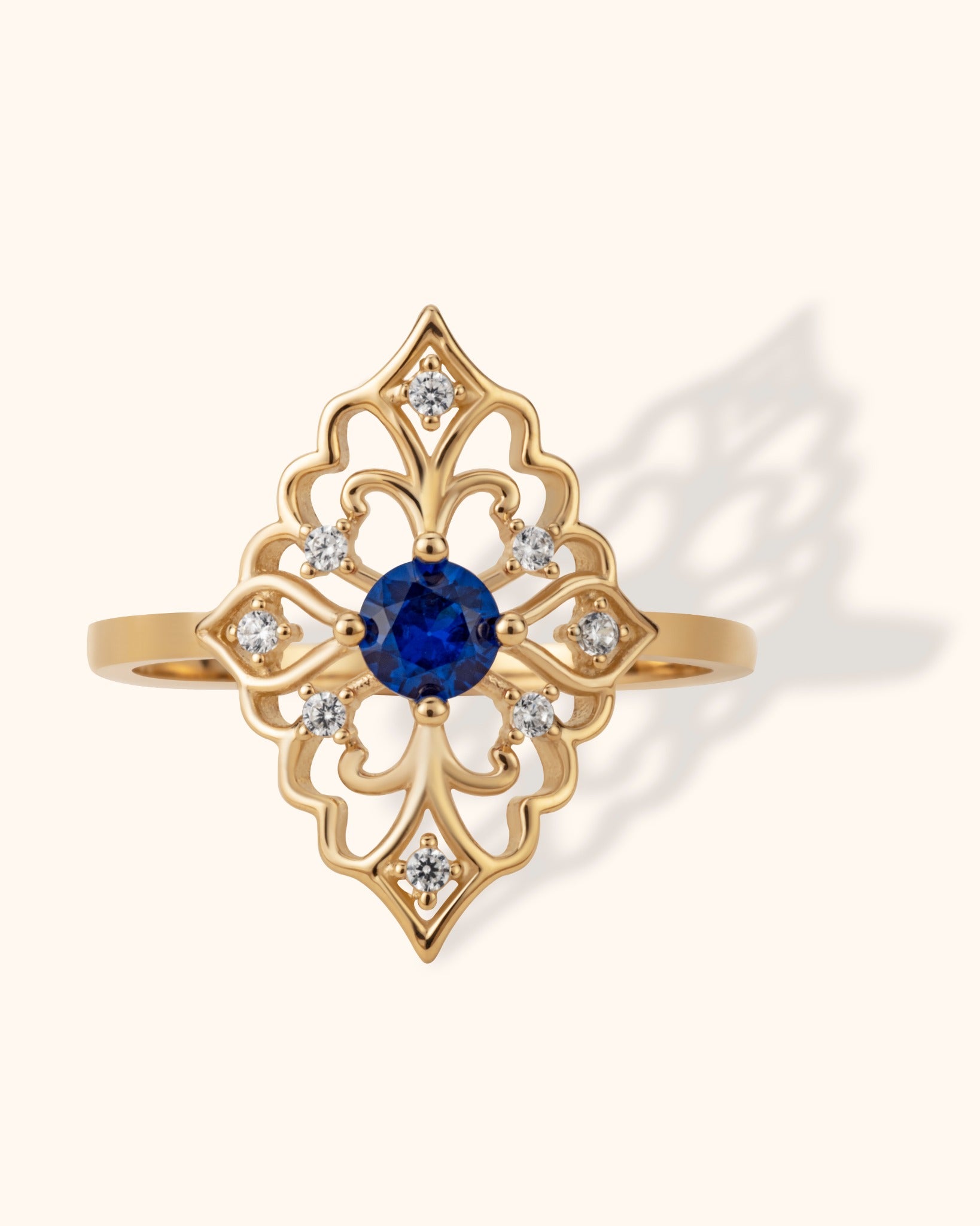Gold filigree ring with round blue sapphire center and surrounding diamonds