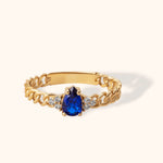 14K gold chain-style ring with pear-shaped deep blue sapphire and accent diamonds