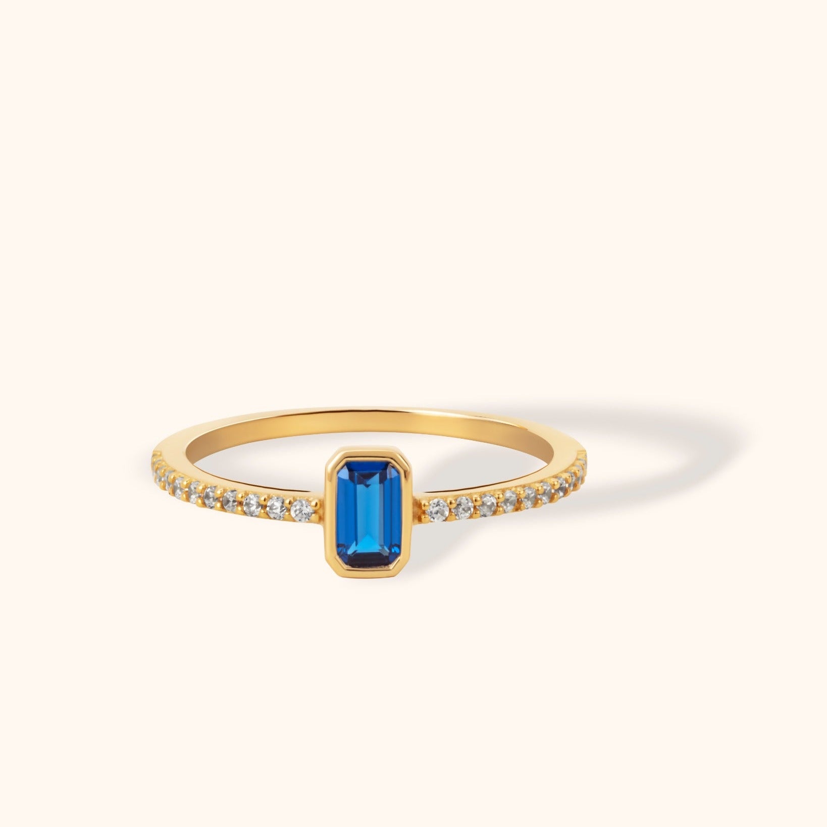 Emerald-cut sapphire gemstone ring set in 14K yellow gold with pavé zircon accents along the band.