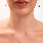 Model wearing a 14K gold plated teardrop sapphire necklace with bird charm and matching threader earrings

