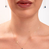 Model wearing a 14K gold plated teardrop sapphire necklace with bird charm and matching threader earrings

