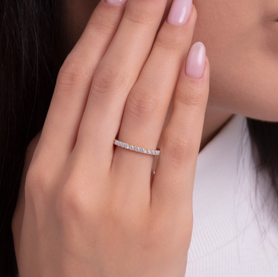 A minimalist eternity band ring with full row of stones on a woman's finger