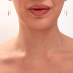 Woman wearing minimalist gold cross necklace and threader earrings

