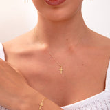Model wearing gold cross jewelry set – necklace, earrings, bracelet