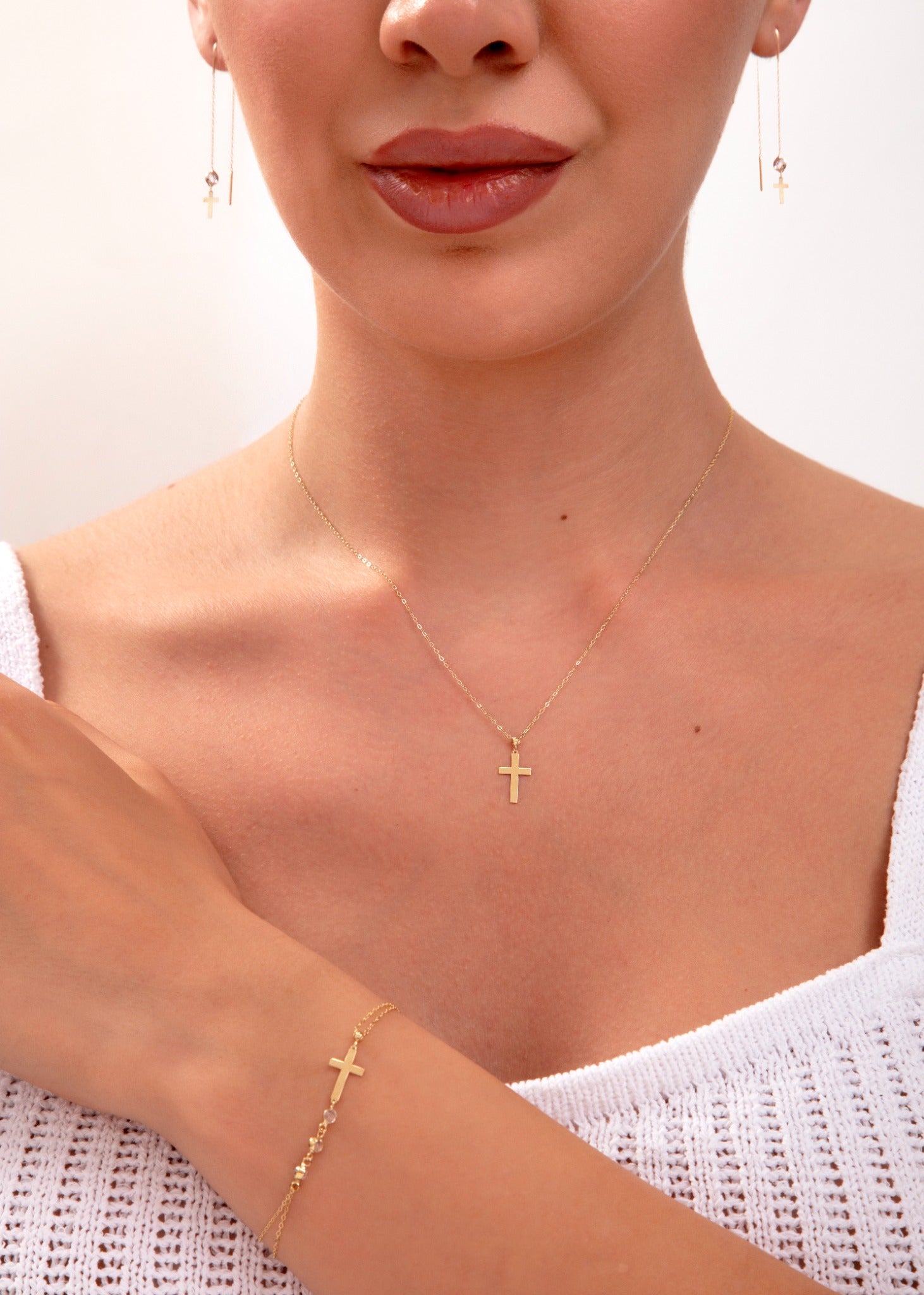 Model wearing gold cross jewelry set – necklace, earrings, bracelet