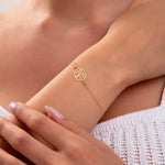 Close-up of a woman wearing a 14K gold plated Tree of Life bracelet with minimalist chain on wrist


