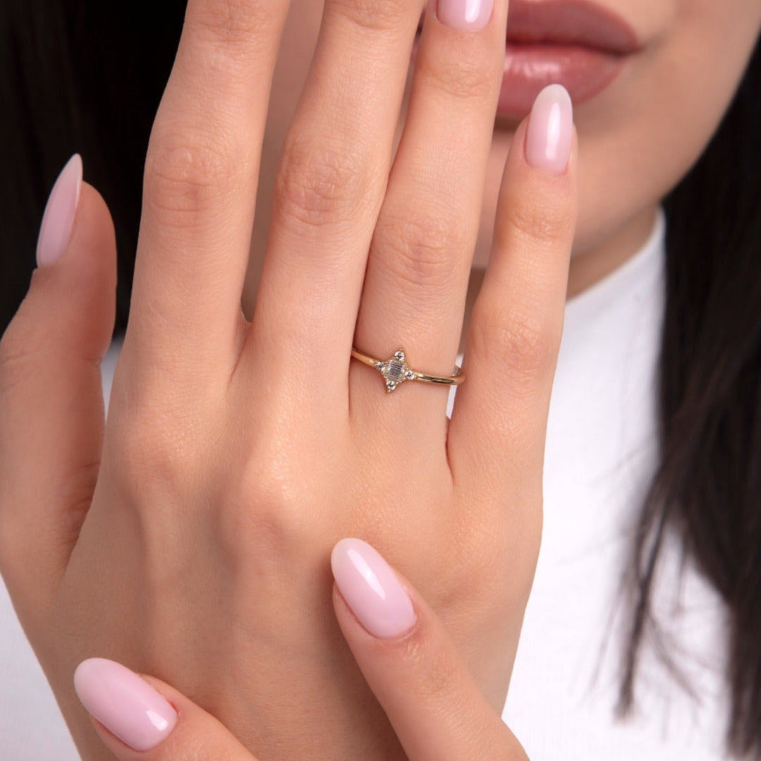 Gold v-shaped stacking ring with small stones on woman's finger, elegant hand pose