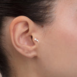 ear model wearing triple stone gold cartilage earring helix piercing