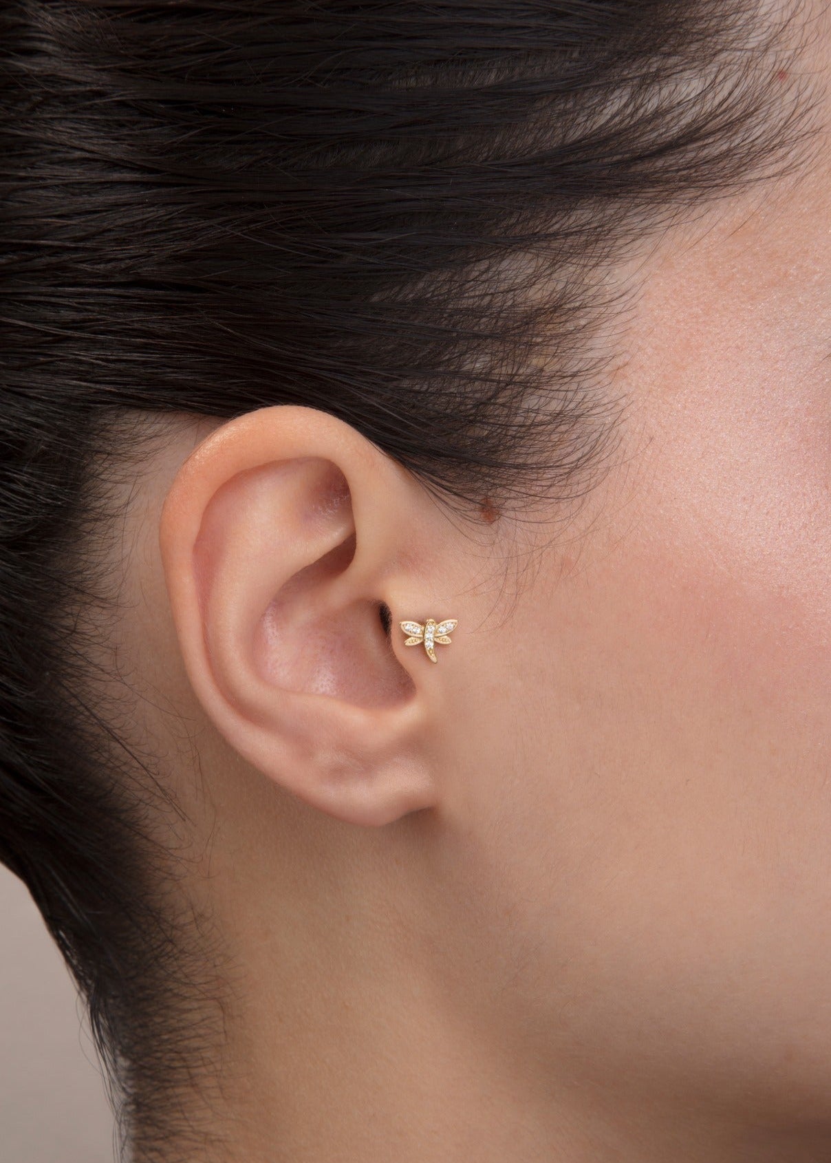 ear model wearing butterfly gold tragus earring suitable for helix cartilage