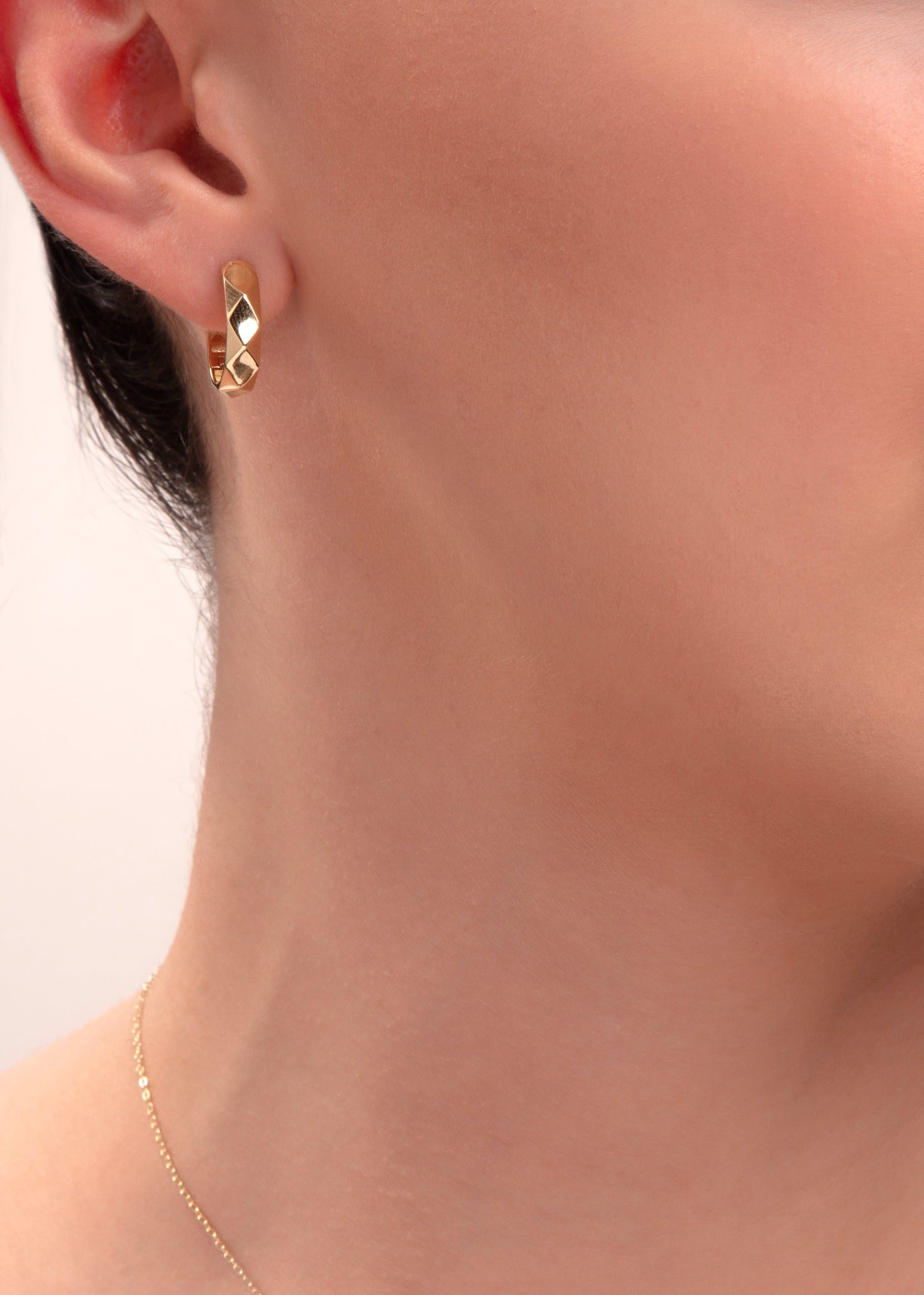 close-up of geometric gold huggie hoop earring