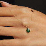 14K gold necklace with emerald teardrop pendant and butterfly charm worn on model’s neck