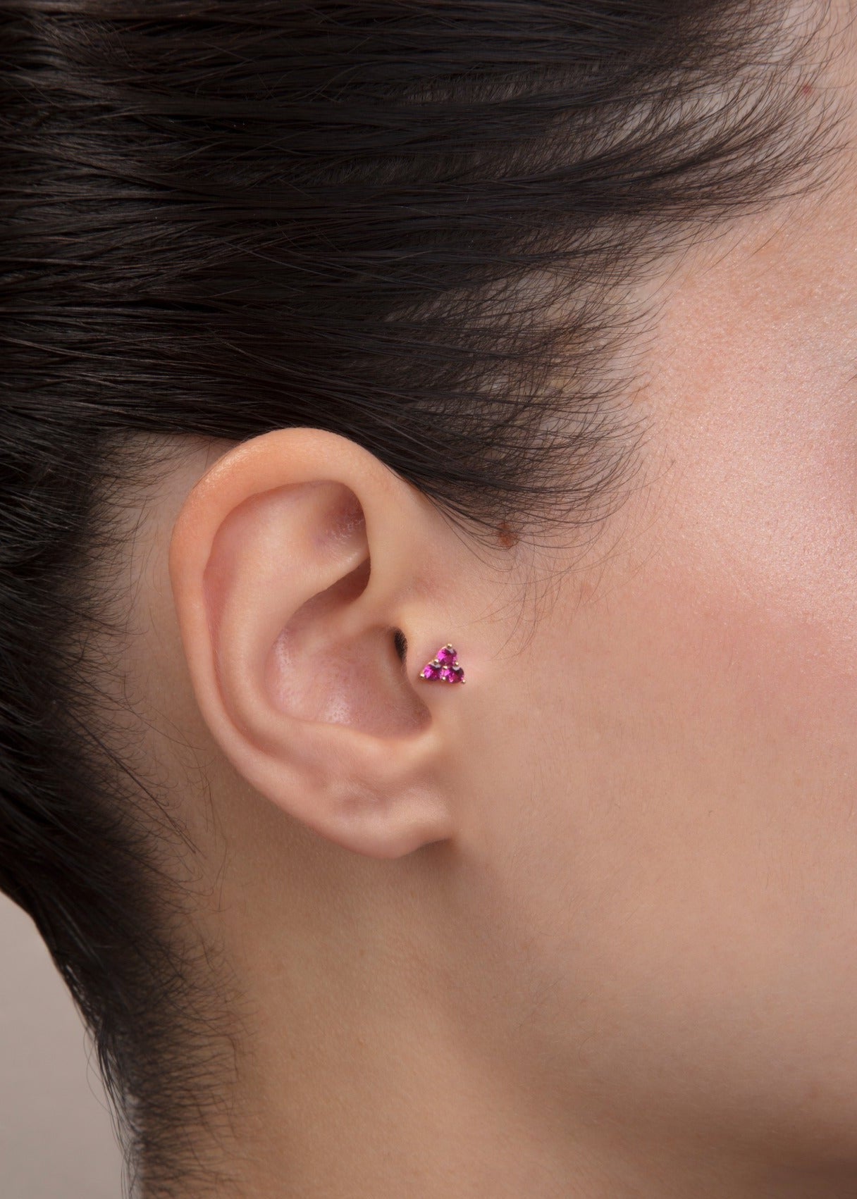 ear model wearing pink cluster gold tragus earring for helix cartilage