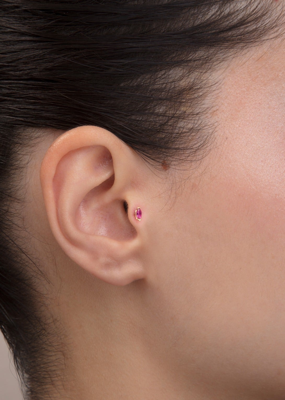 ear model wearing pink stone gold tragus earring suitable for helix cartilage