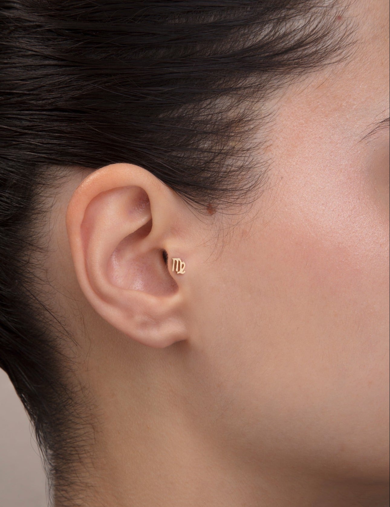 ear model wearing virgo zodiac gold tragus earring for helix cartilage