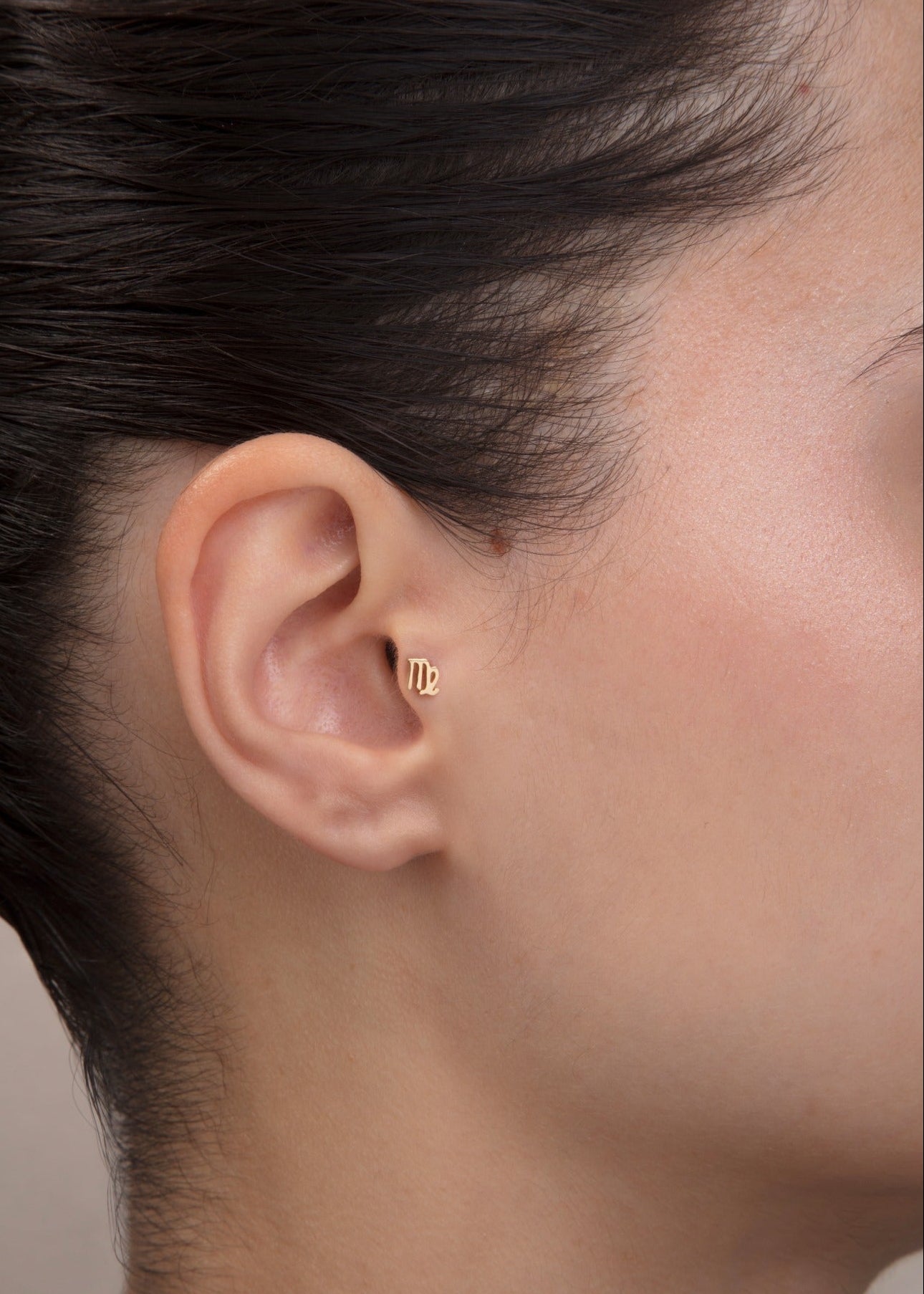 ear model wearing virgo zodiac gold tragus earring for helix cartilage