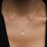 14K gold necklace featuring a radiant sunburst charm with pointed rays and a hollow center,
