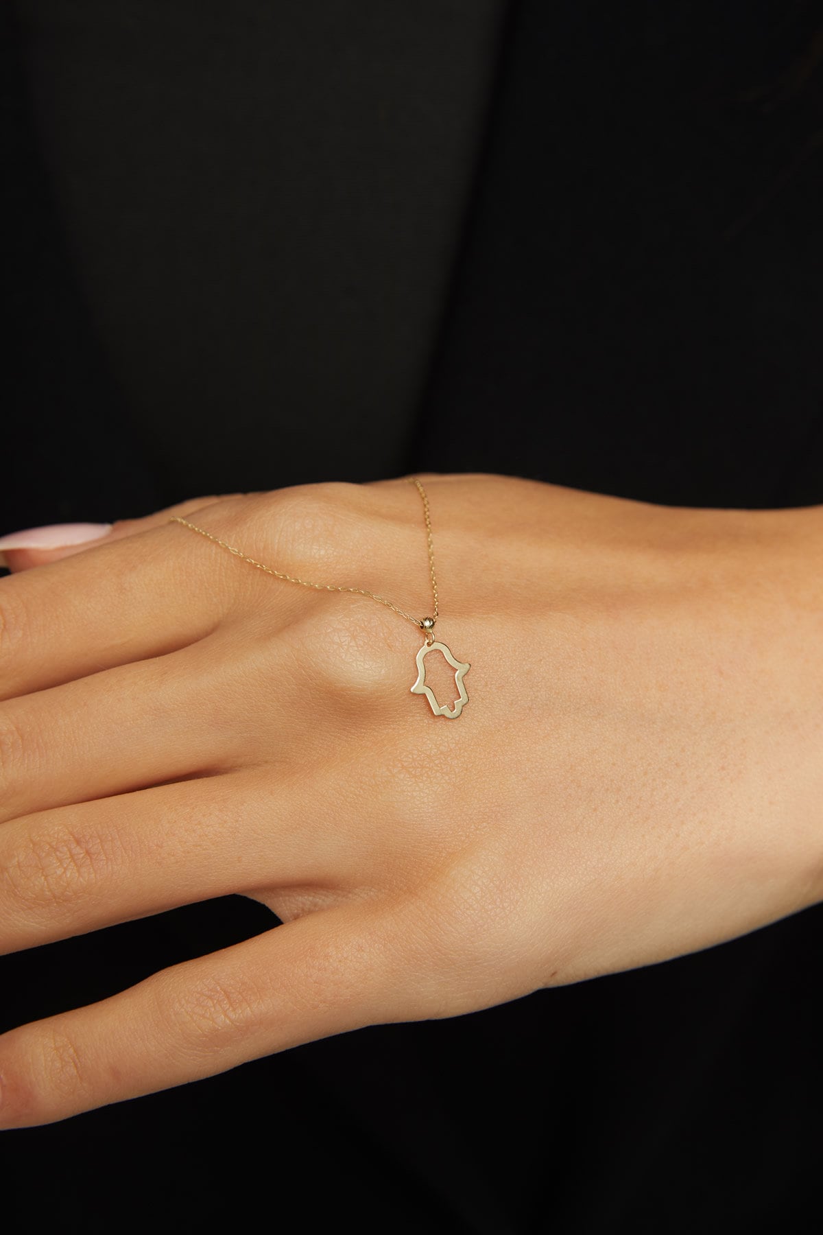 14K gold Hamsa hand necklace on emerald