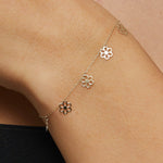 Dainty 14K gold bracelet with multiple hanging flower charms  – floral station design.