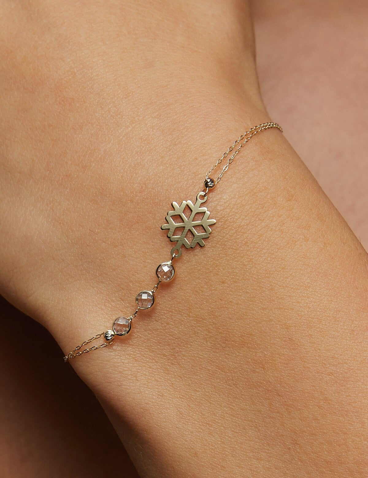Elegant 14K gold bracelet featuring a snowflake charm and crystal bead accents