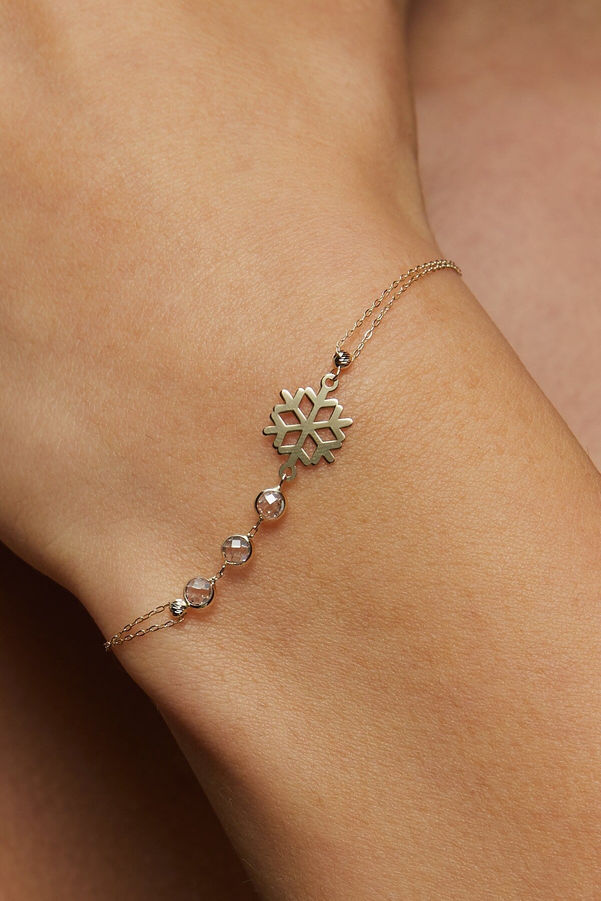 Elegant 14K gold bracelet featuring a snowflake charm and crystal bead accents