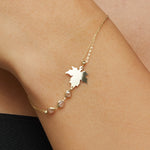 14K gold bracelet with maple leaf charm and gemstone accents on green satin