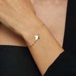 14K gold bracelet with maple leaf charm and gemstone accents on green satin