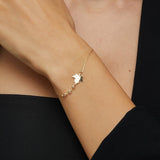 14K gold bracelet with maple leaf charm and gemstone accents on green satin