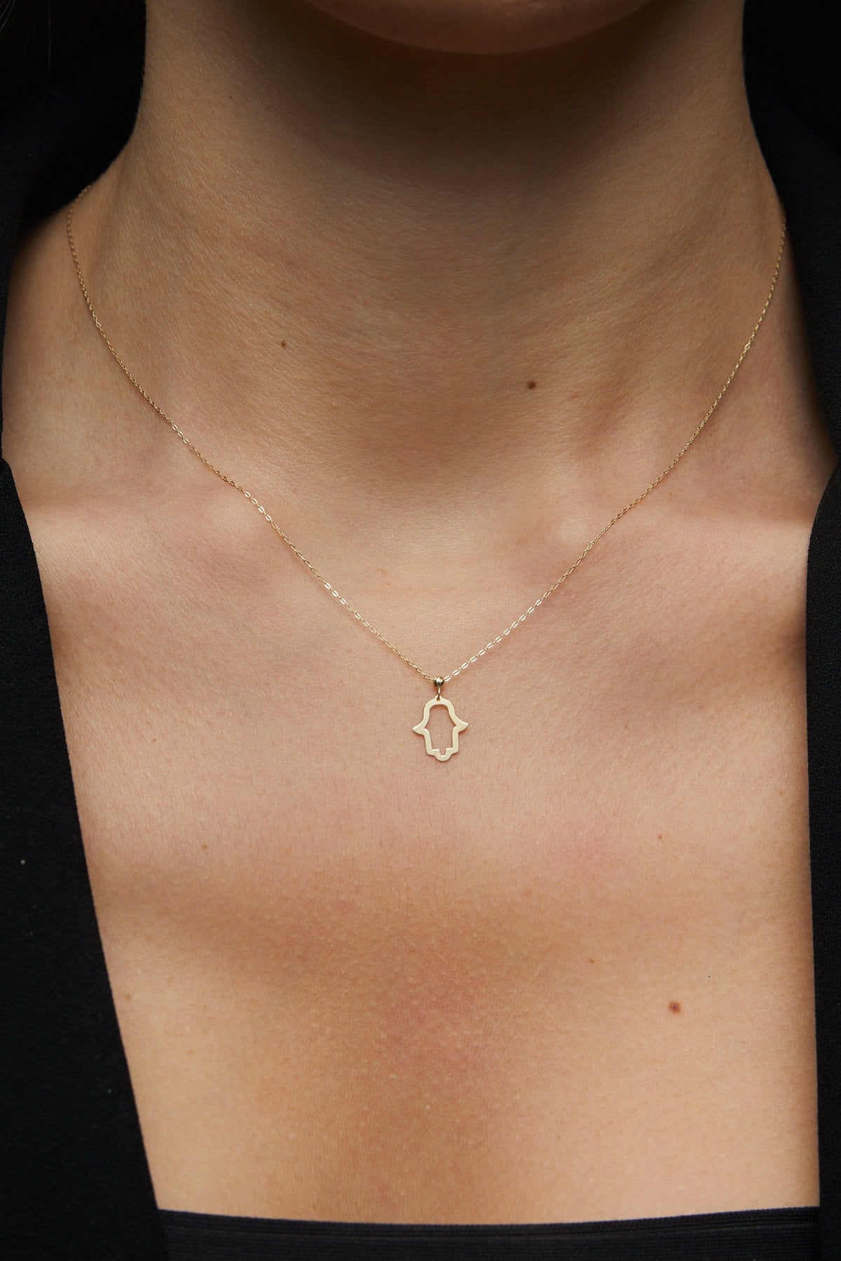 14K gold Hamsa hand necklace on emerald