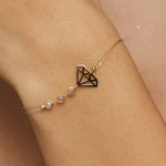 14K gold bracelet with geometric diamond outline and faceted gemstone bead accents on green silk background