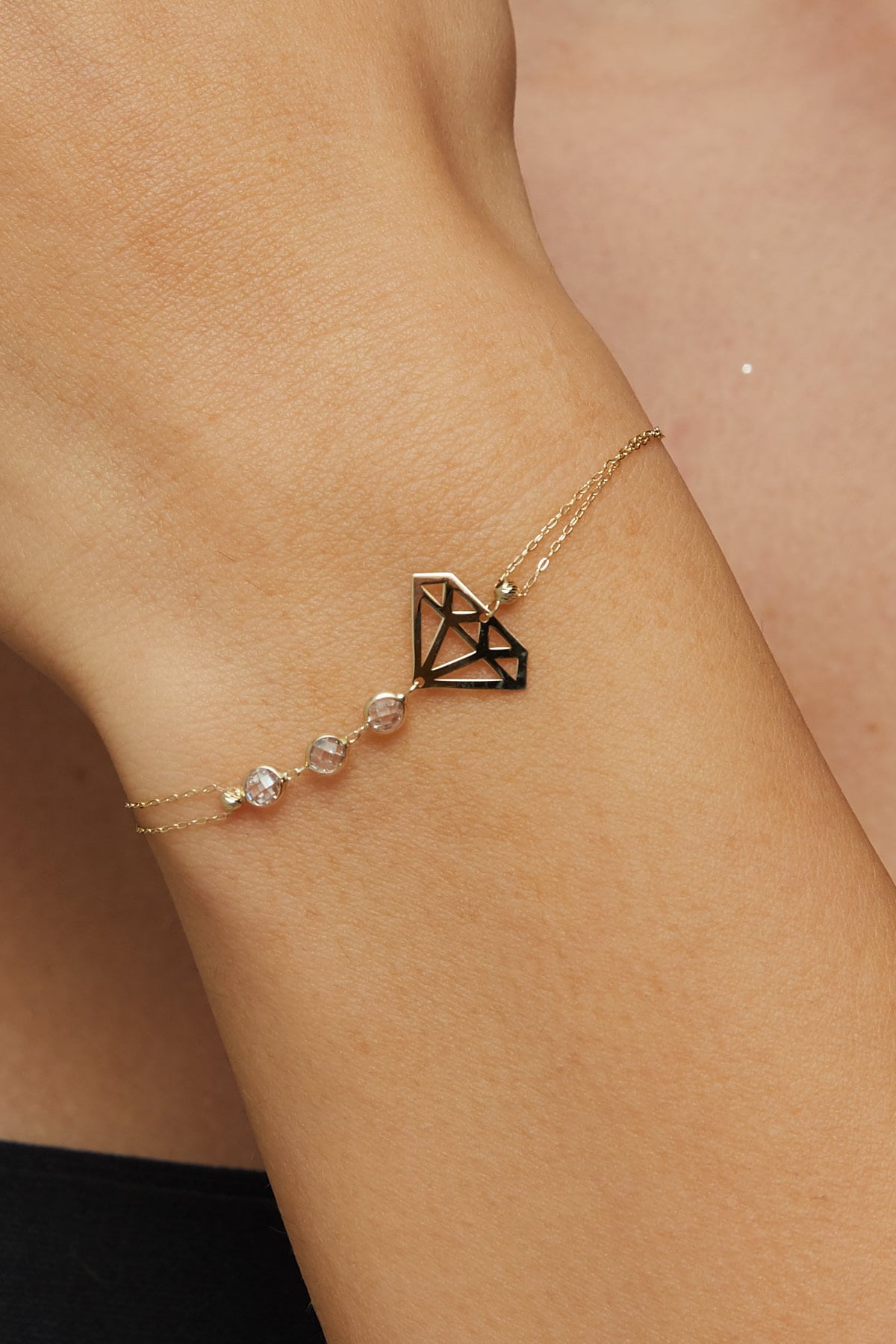 14K gold bracelet with geometric diamond outline and faceted gemstone bead accents on green silk background