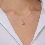 Minimal 14K gold necklace featuring a four-leaf clover charm hanging from a twisted circle,