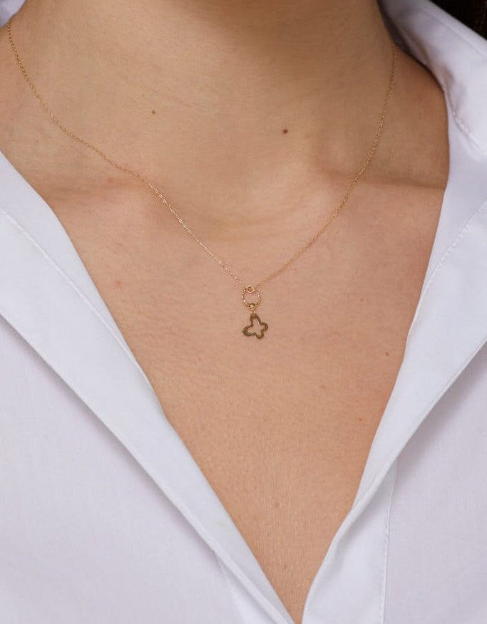 Minimal 14K gold necklace featuring a four-leaf clover charm hanging from a twisted circle,