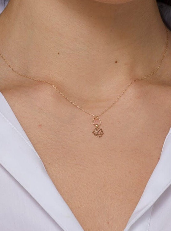 Elegant 14K gold necklace featuring a textured circle and a lotus flower pendant
