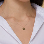 Minimalist 14K gold medallion necklace with a central cutout cross and radiant sunbeam engravings