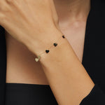 Close-up of 14K gold bracelet with five dangling heart charms – perfect for gift-giving or everyday wear