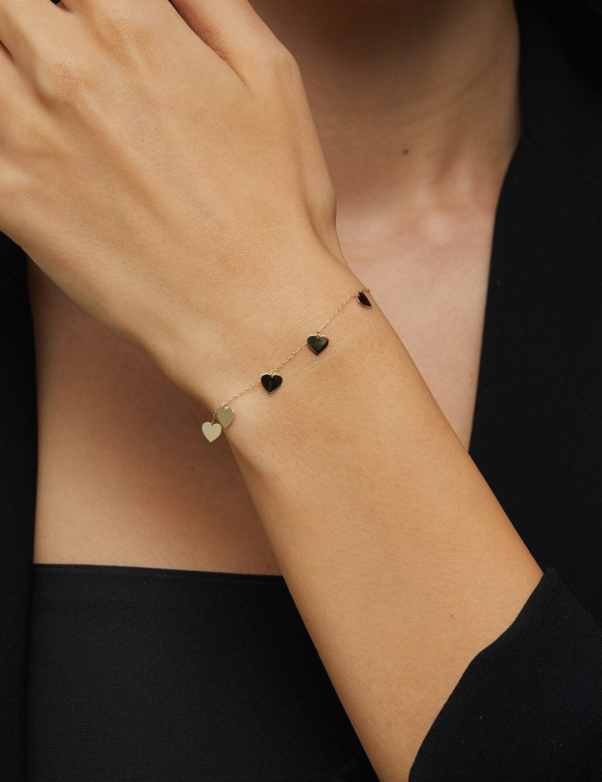 Close-up of 14K gold bracelet with five dangling heart charms – perfect for gift-giving or everyday wear
