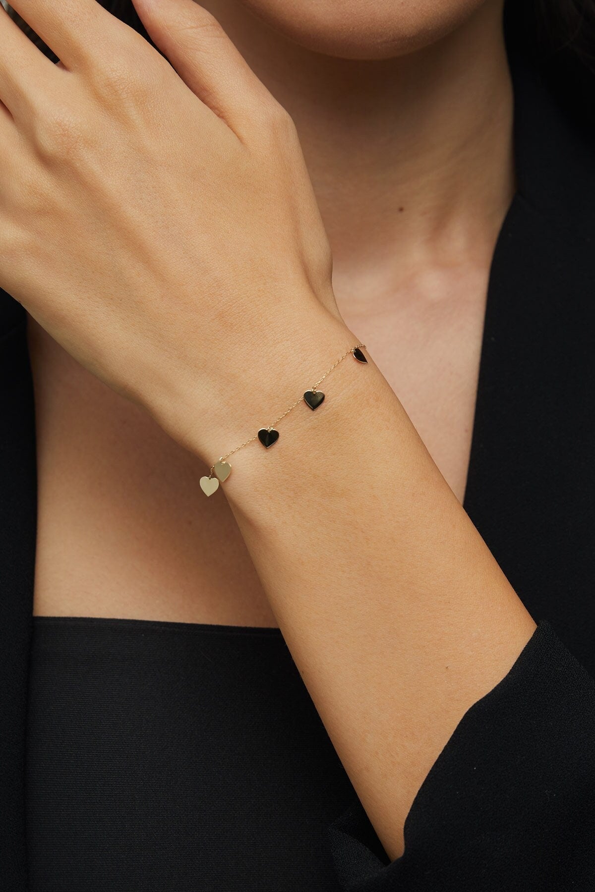 Close-up of 14K gold bracelet with five dangling heart charms – perfect for gift-giving or everyday wear