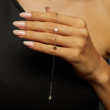 Minimalist 14K gold bracelet with clover-shaped charms and tiny textured accents, styled on emerald green silk fabric