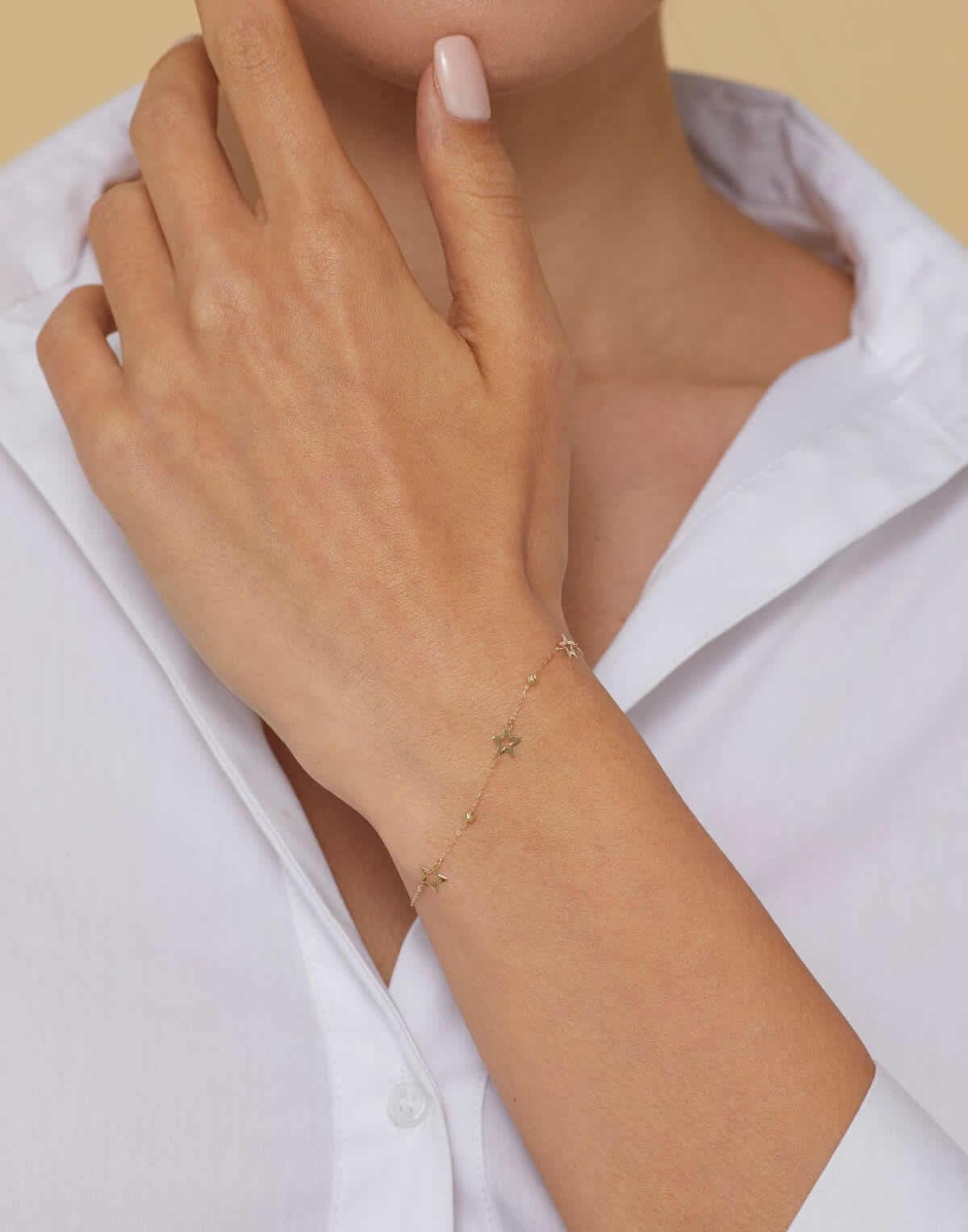 Close-up of a 14K gold bracelet with hollow star charms and gold beads