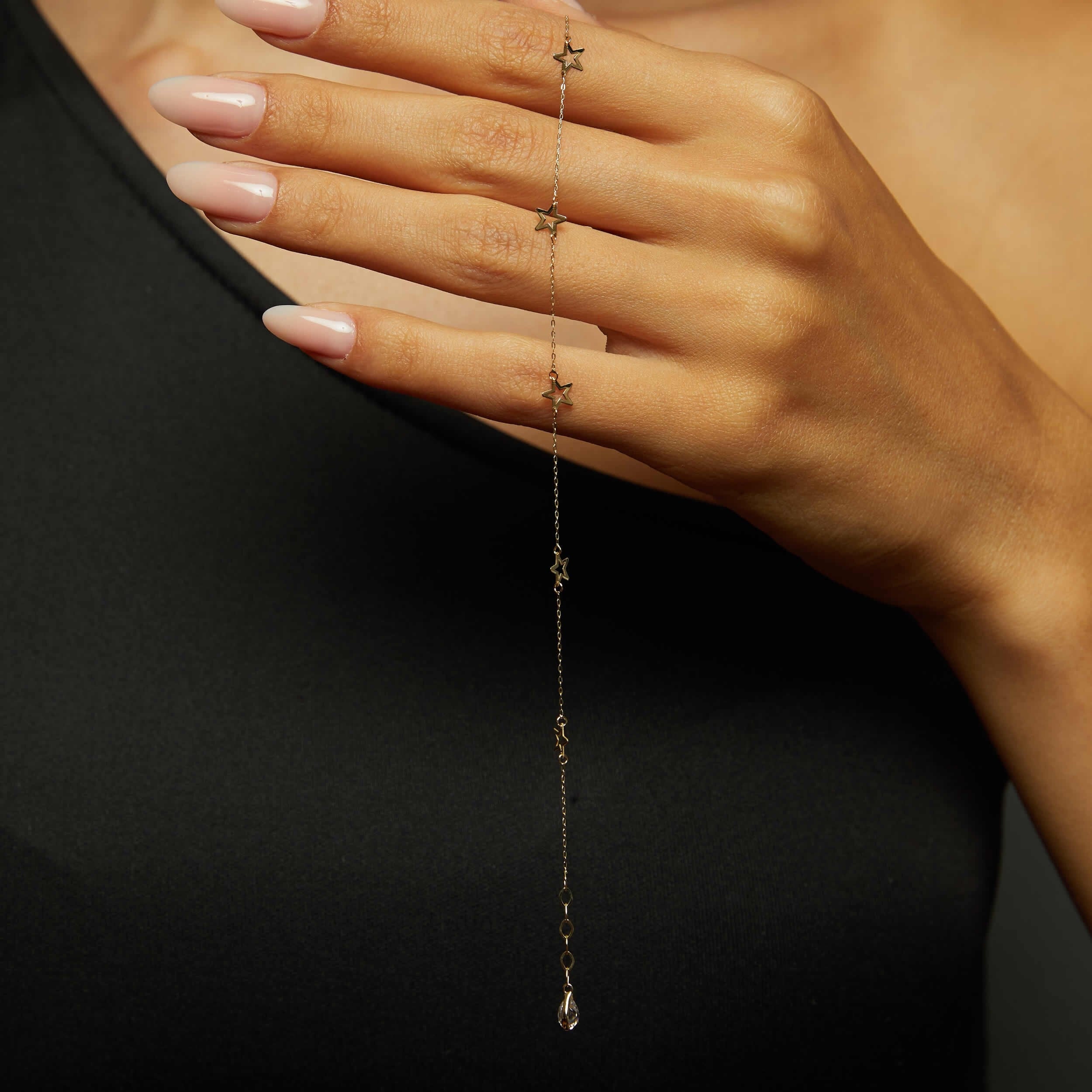 14K gold bracelet with delicate open star charms on green fabric