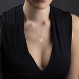 14K gold Flower of Life pendant necklace on deep purple fabric – sacred geometry jewelry with spiritual symbolism.