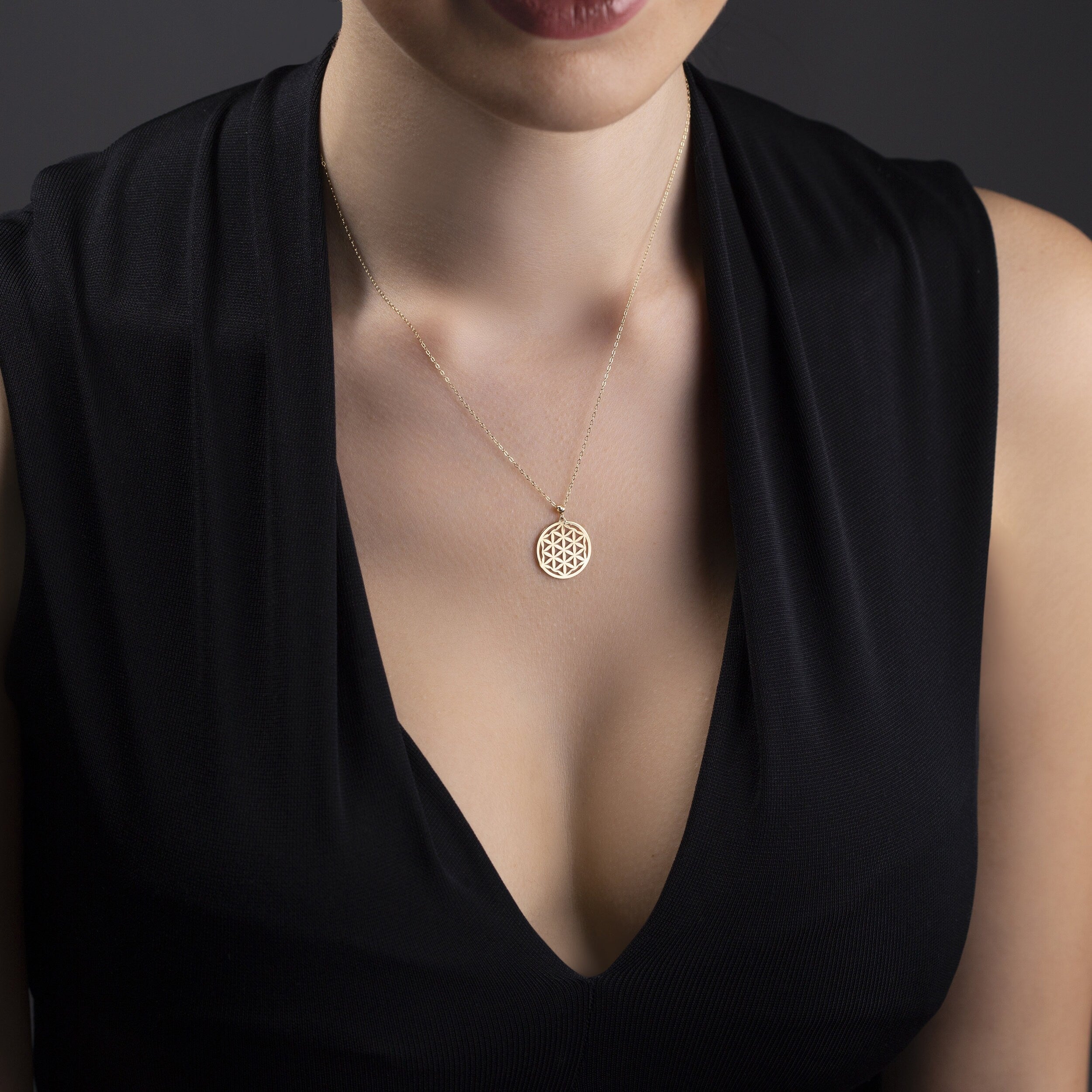 14K gold Flower of Life pendant necklace on deep purple fabric – sacred geometry jewelry with spiritual symbolism.